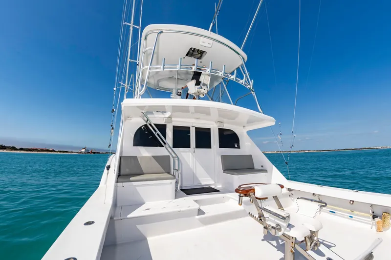 Slide: The Image of The image shows a 2000 Custom Carolina Terry Guthrie Sportfish boat. It features a spacious deck with seating and fishing rod holders. The sky is clear and the water is turquoise. - 12