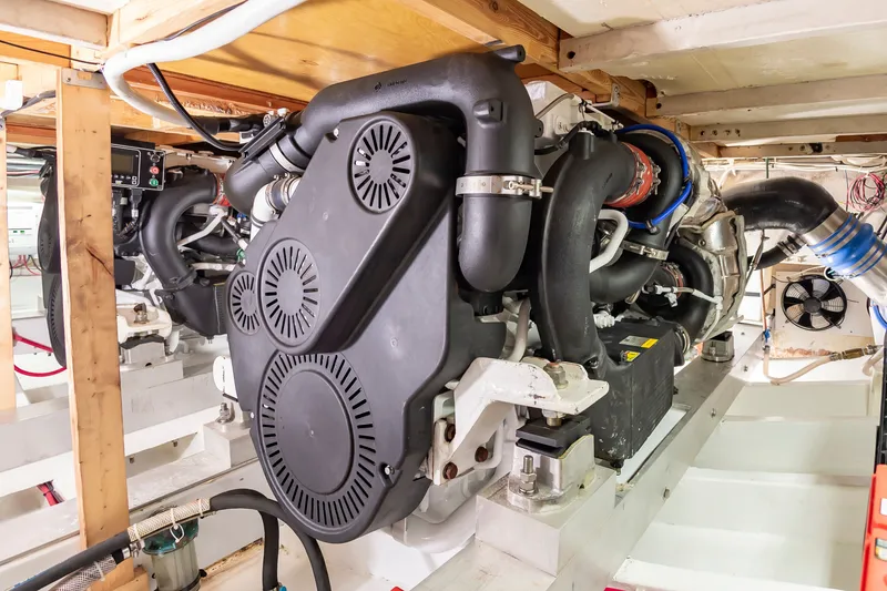 Slide: The Image of The engine room of a 2000 Custom Carolina Terry Guthrie Sportfish features a large engine with black covers and piping. - 29