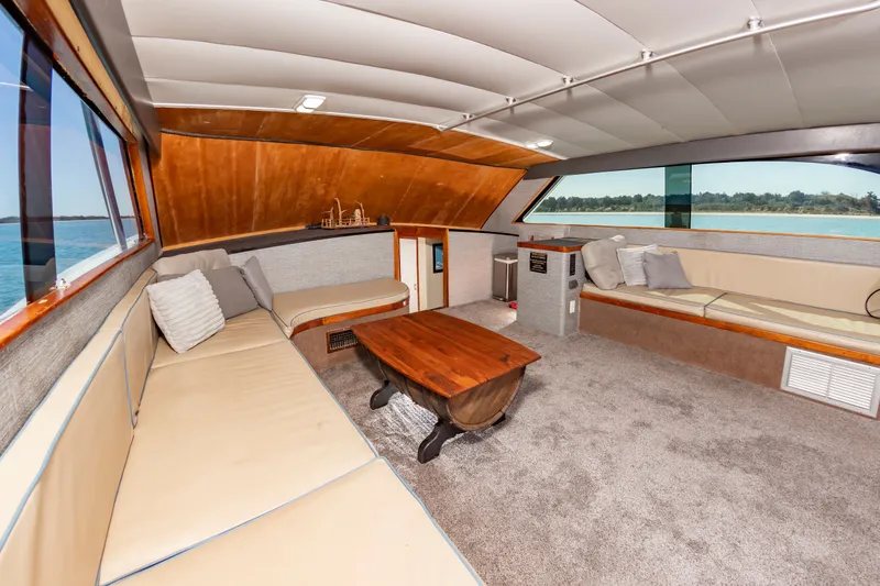 Slide: The Image of The interior of a 2000 Custom Carolina Terry Guthrie Sportfish features a spacious lounge with beige sofas and a wooden table. - 22