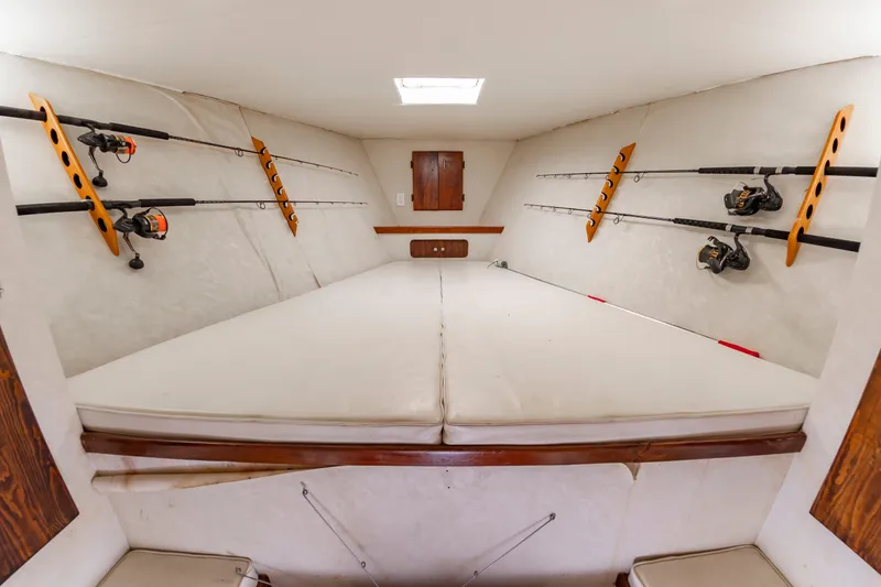 Slide: The Image of The interior of a sportfishing boat with multiple fishing rods on the walls and a cushioned sleeping area. - 45