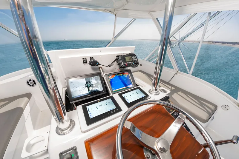 Slide: The Image of The image shows the helm of a 2000 Custom Carolina Terry Guthrie Sportfish. It features modern navigation equipment and a sleek wooden steering wheel. - 16