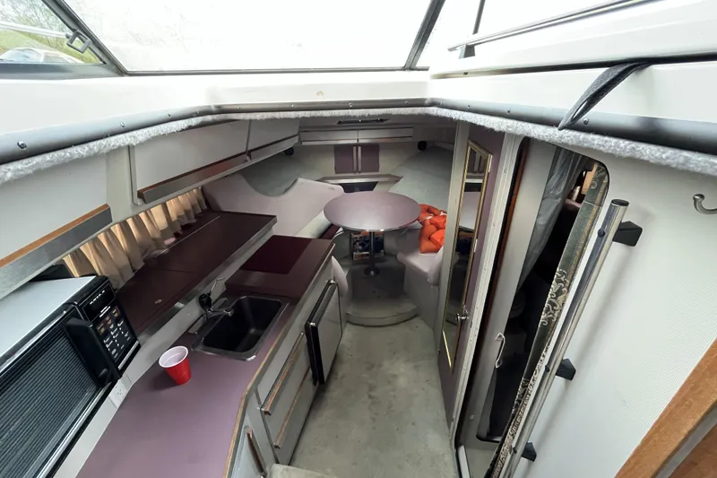 Slide: The Image of Interior of a 1987 Carver 2757 Montego boat, featuring a compact kitchen and dining area. - 6