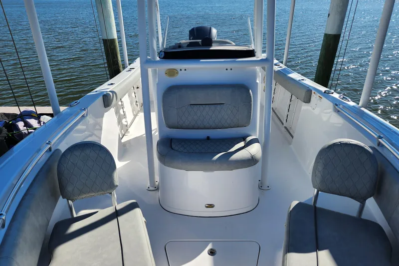 Slide: The Image of 2020 Sportsman Open 232 Center Console boat interior with seating, docked by the water. - 22