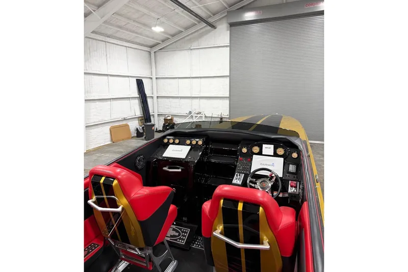 Slide: The Image of 2018 Cigarette 42X boat interior with red seats and advanced dashboard in a garage. - 11