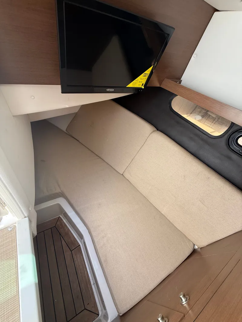 Slide: The Image of Interior of the 2018 Sea Ray SLX 350 Outboard with a sofa and TV. - 22