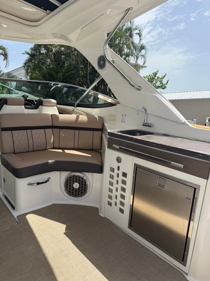 Slide: The Image of The image shows the interior of a 2018 Sea Ray SLX 350 Outboard with seating area and sink. - 19