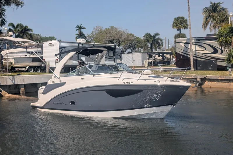 The Image of 2023 Regal 26 XO boat cruising in a marina with palm trees in the background. - 1