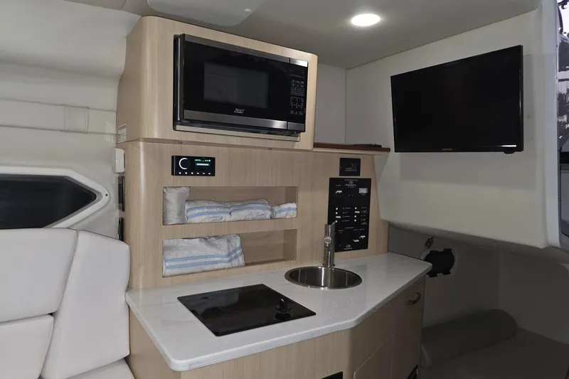 Slide: The Image of 2023 Regal 26 XO boat interior with kitchenette, microwave, sink, and TV. - 10