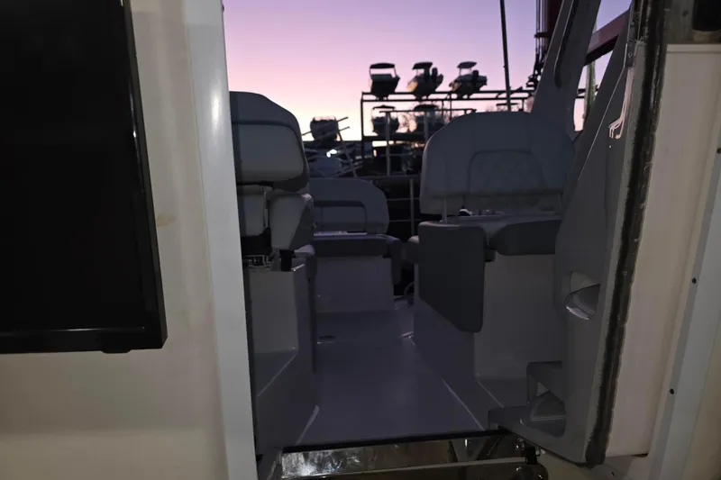 Slide: The Image of 2023 Regal 26 XO boat interior at sunset, showcasing seating and helm area. - 11