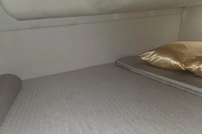 Slide: The Image of 2023 Regal 26 XO cabin interior with gray bedding and gold pillows. - 9