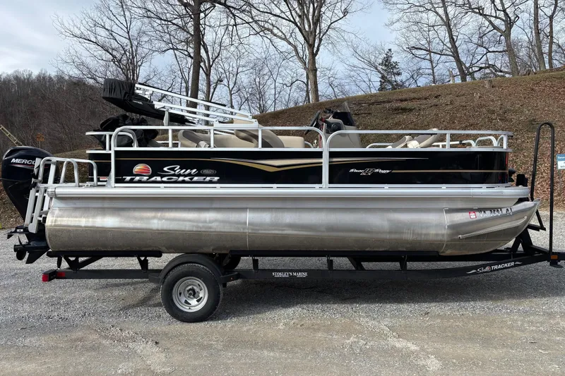 Slide: The Image of 2022 Sun Tracker Bass Buggy 18 DLX pontoon boat on trailer, parked outdoors. - 6