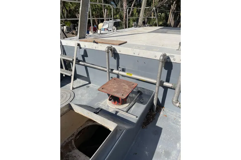 Slide: The Image of 1987 Commercial Buoy Tender deck with railing and open hatch, surrounded by trees. - 16