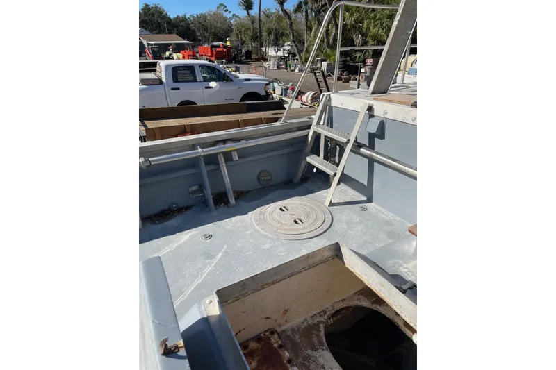 Slide: The Image of 1987 Commercial Buoy Tender deck with ladder, surrounded by equipment and vehicles. - 17