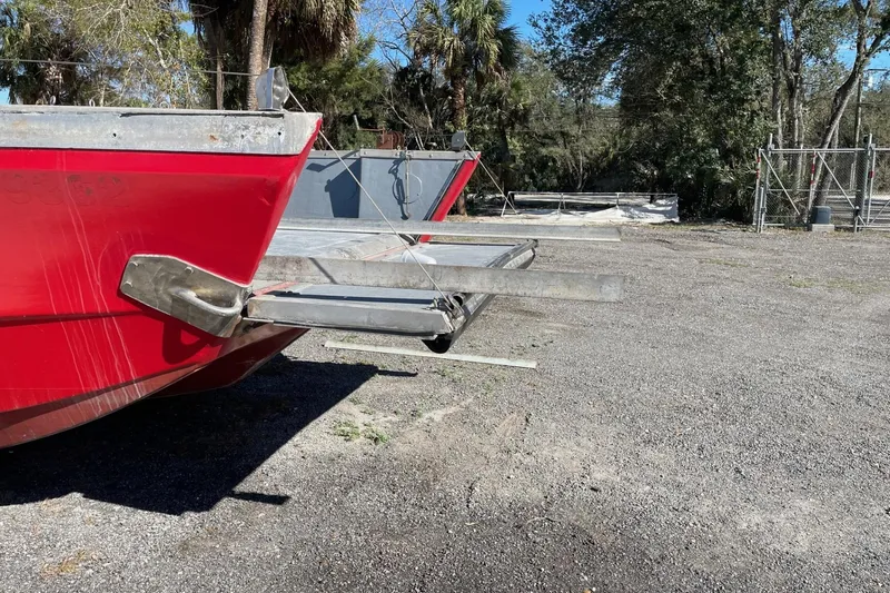 Slide: The Image of Red 1987 Commercial Buoy Tender with metal extension, parked on gravel near trees. - 2
