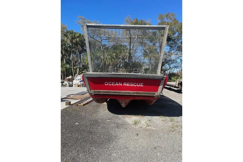 Slide: The Image of Red 1987 Commercial Buoy Tender labeled "Ocean Rescue" on land with trees in background. - 25