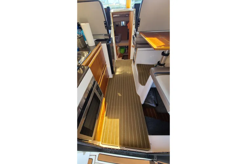 Slide: The Image of 2019 Cutwater C-28 LE interior with kitchenette, seating, and wood accents. - 22