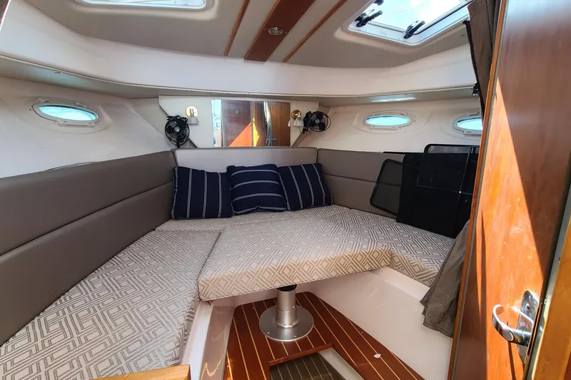 Slide: The Image of 2019 Cutwater C-28 LE cabin interior with cozy bedding and striped pillows. - 25