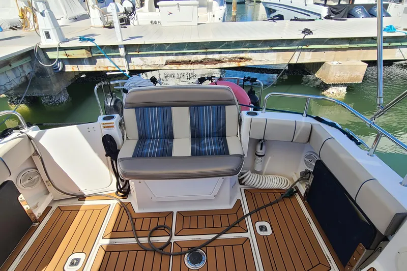 Slide: The Image of 2019 Cutwater C-28 LE boat interior with striped seating and teak flooring at a marina. - 4