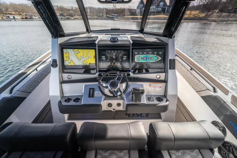 Slide: The Image of 2025 Fountain 43 SCX boat dashboard with navigation screens and steering wheel on a lake. - 22
