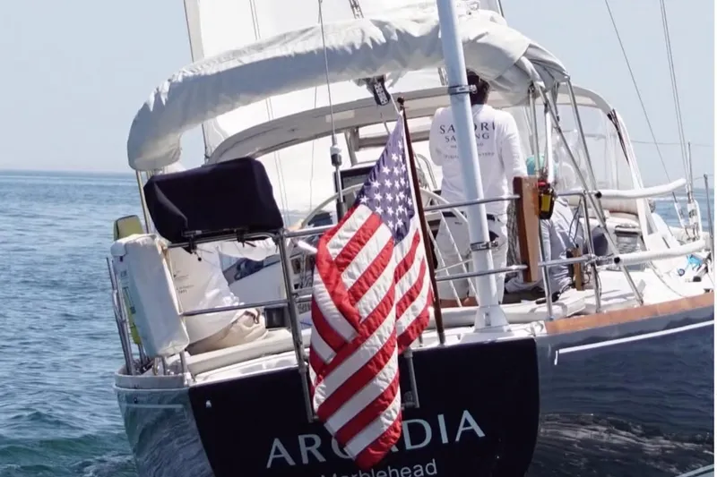 Slide: The Image of 1997 J/42 sailboat with American flag on the water. - 12