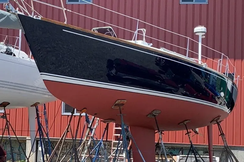 Slide: The Image of 1997 J Boats J/42 sailboat on stands, red hull, against a red building background. - 7