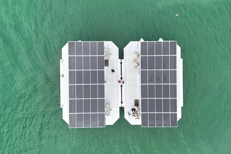 Slide: The Image of Aerial view of ARKHAUS Villa 50, 2025, with solar panels on turquoise water. - 19