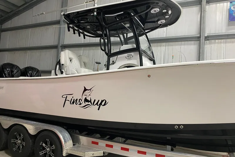 Slide: The Image of 2021 Sportsman Open 282 Center Console boat in a garage, featuring "Fins Up" decal. - 2