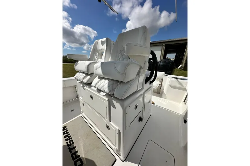 Slide: The Image of 2021 Sportsman Open 282 Center Console with white cushioned seating under a blue sky. - 32