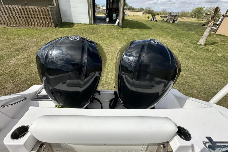 Slide: The Image of 2021 Sportsman Open 282 Center Console with dual outboard engines, parked on grass. - 58