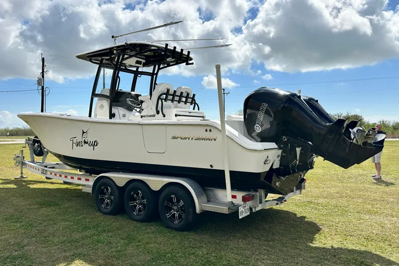 Slide: The Image of 2021 Sportsman Open 282 Center Console boat on trailer, parked on grass under cloudy sky. - 7
