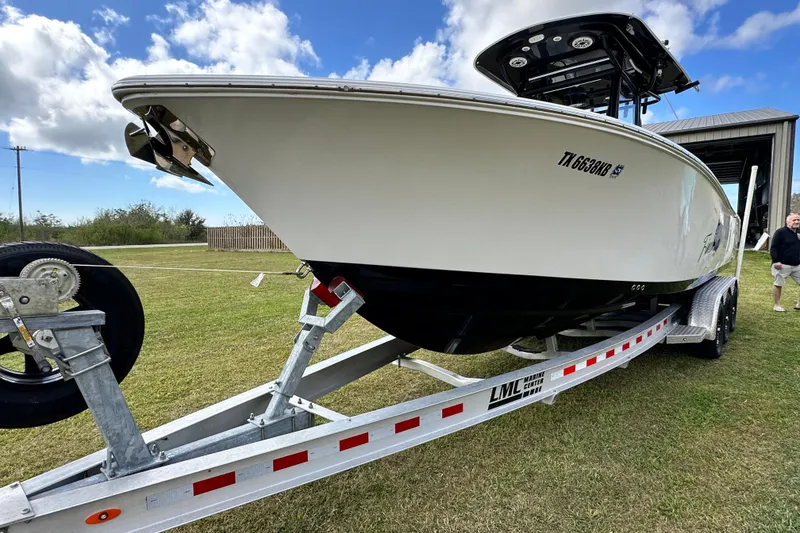 Slide: The Image of 2021 Sportsman Open 282 Center Console boat on trailer, grassy area, blue sky. - 8