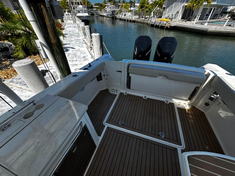 Slide: The Image of 2019 Boston Whaler 270 Vantage boat interior with wooden deck, docked by a canal. - 17