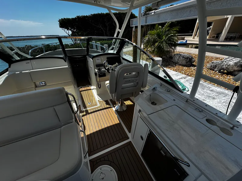 Slide: The Image of 2019 Boston Whaler 270 Vantage boat interior with seating and helm, docked by the shore. - 23