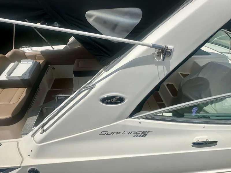 Slide: The Image of 2012 Sea Ray 310 Sundancer boat, sleek design, white exterior, partial view of seating area. - 10