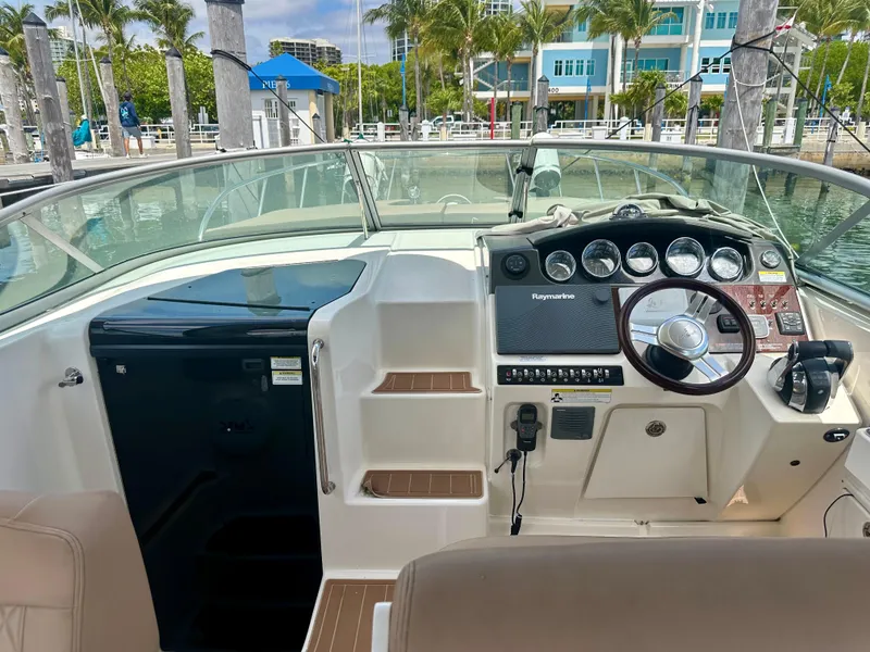 Slide: The Image of 2012 Sea Ray 310 Sundancer cockpit with steering wheel, gauges, and seating at marina. - 25