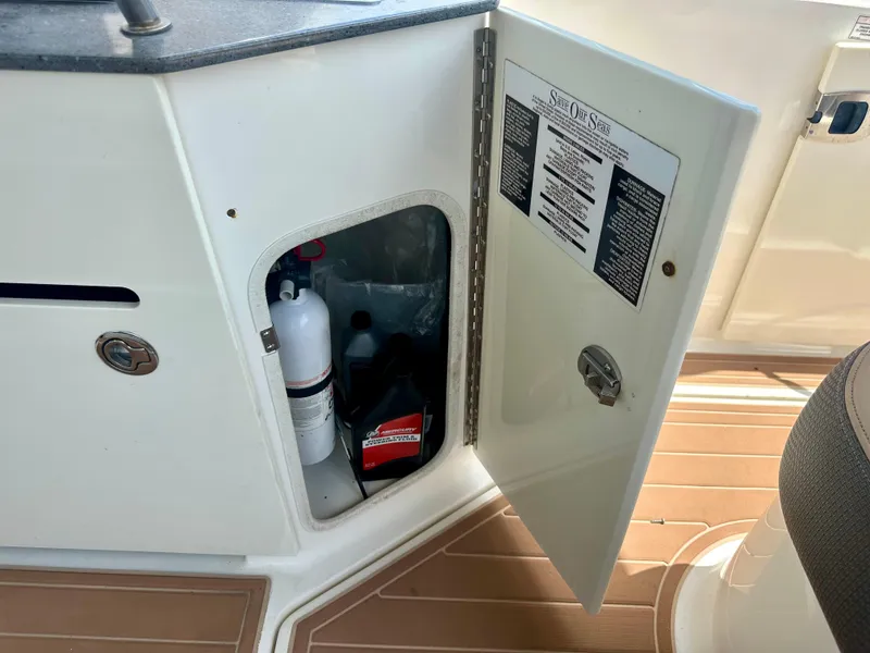 Slide: The Image of Open storage compartment on 2012 Sea Ray 310 Sundancer boat, showing safety equipment. - 33