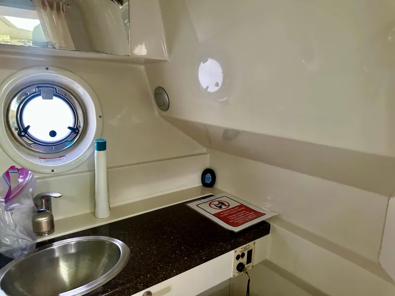 Slide: The Image of Interior of 2012 Sea Ray 310 Sundancer boat, featuring a compact sink and porthole. - 48