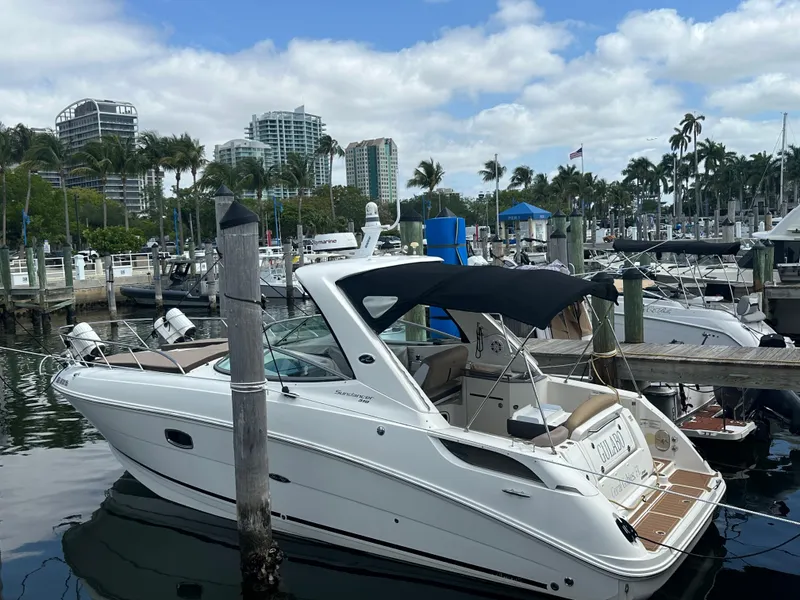 Slide: The Image of 2012 Sea Ray 310 Sundancer docked at a marina with cityscape background. - 6