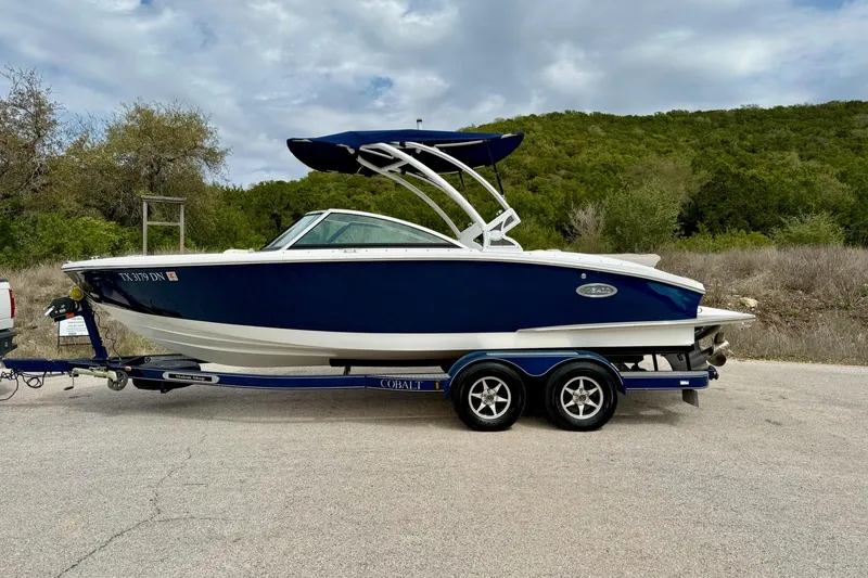 Slide: The Image of 2016 Cobalt CS3 boat on trailer, parked outdoors with lush greenery background. - 11