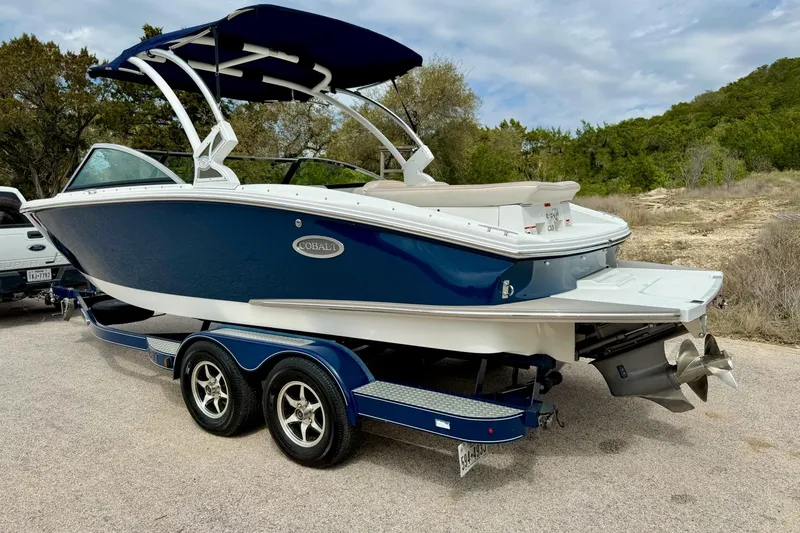 Slide: The Image of 2016 Cobalt CS3 boat on trailer, blue and white, parked outdoors. - 12