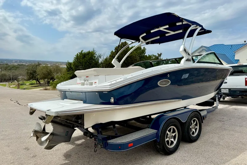 Slide: The Image of 2016 Cobalt CS3 boat on trailer, blue and white design, parked outdoors. - 15