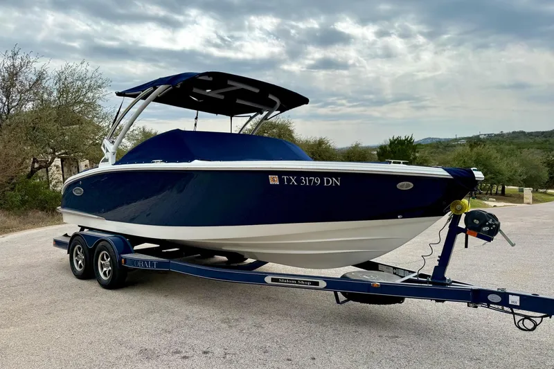 Slide: The Image of 2016 Cobalt CS3 boat on trailer, blue hull, parked outdoors under cloudy sky. - 16