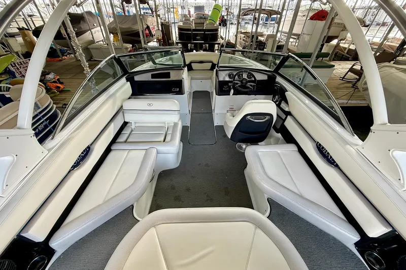 Slide: The Image of 2016 Cobalt CS3 boat interior with white seating and modern dashboard in marina setting. - 19