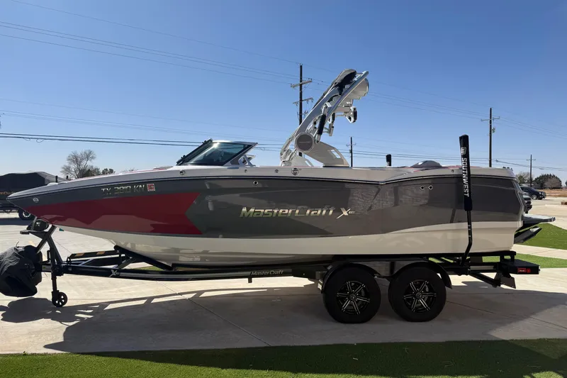 Slide: The Image of 2021 MasterCraft XStar boat on trailer, parked outdoors under clear sky. - 7