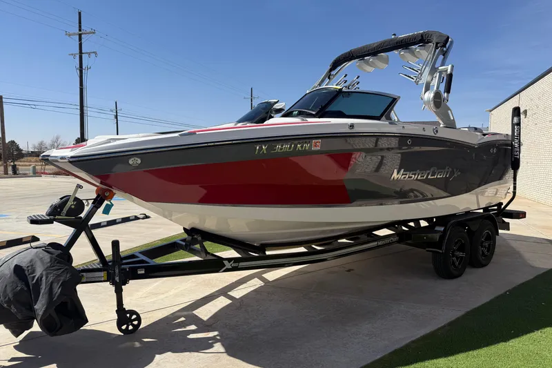 Slide: The Image of 2021 MasterCraft XStar boat on trailer, red and white design, parked outdoors. - 8
