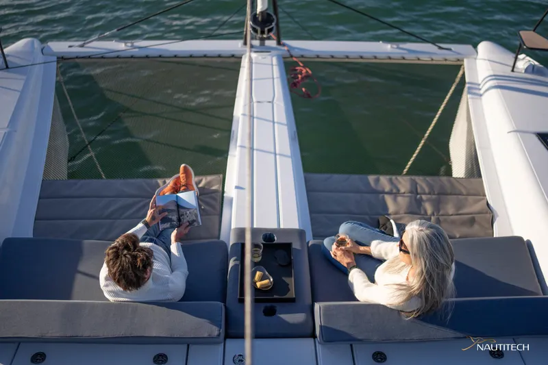 Slide: The Image of Two people relaxing on a 2025 Nautitech 48 Open catamaran deck. - 17