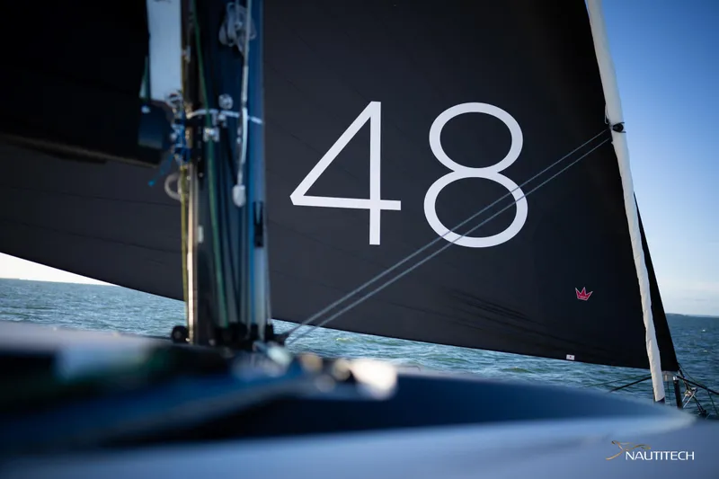 Slide: The Image of Sailing yacht Nautitech 48 Open, 2025 model, with black sail on open water. - 22