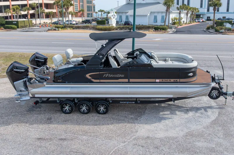 Slide: The Image of 2024 Manitou 25 LX SRW Dual Engine pontoon boat on trailer, parked roadside. - 10