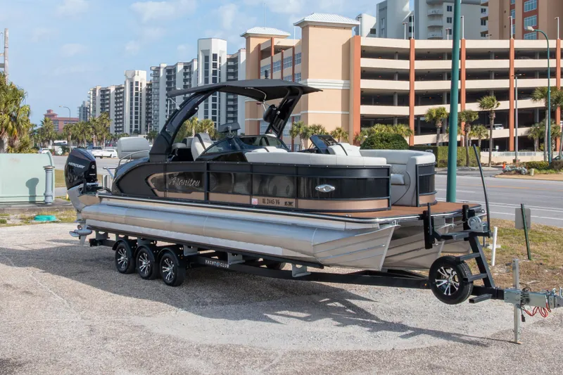 Slide: The Image of 2024 Manitou 25 LX SRW Dual Engine pontoon boat on trailer, urban background. - 11