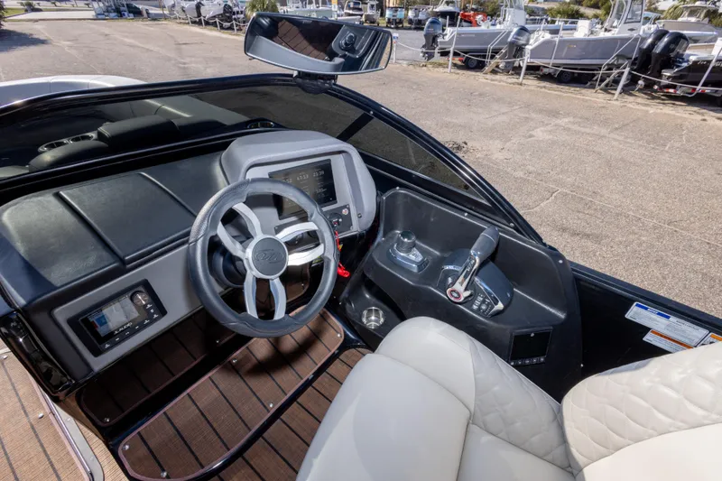 Slide: The Image of 2024 Manitou 25 LX SRW Dual Engine boat cockpit with steering wheel and controls. - 40